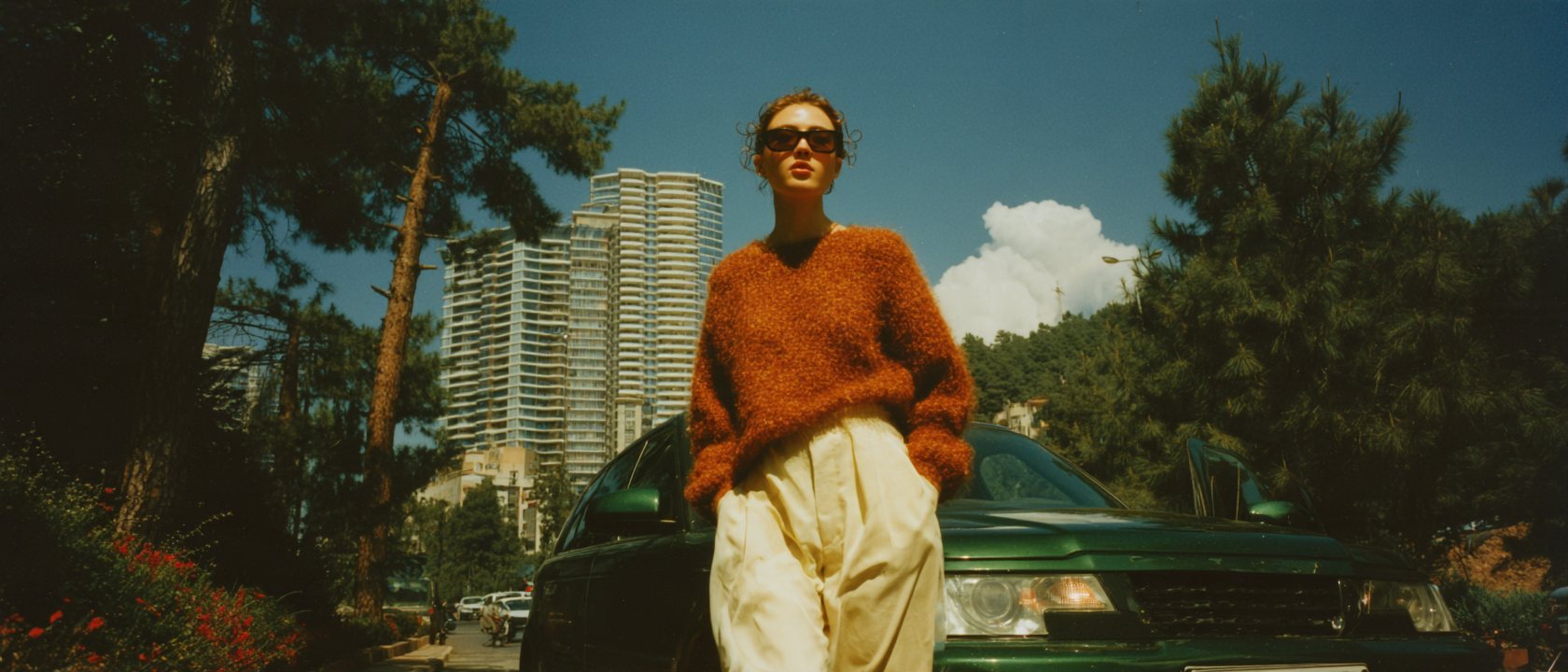 Woman beside a dark green SUV on a city street